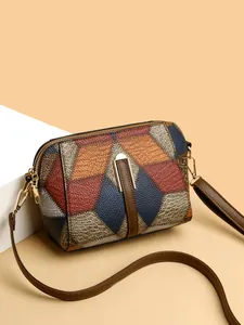 Detailaufnahme der geometrischen Patchwork-Umhängetasche mit goldener Hardware