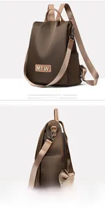 Detail view of brown oxford fabric backpack showing MTW logo and anti-theft side zipper