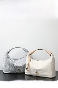 Detailed close-up showing textured leather and elegant metal flower pendants on handbags