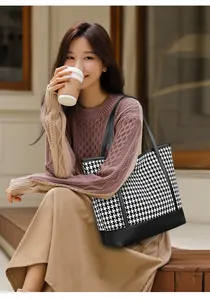 Chic houndstooth pattern tote bag with premium leather straps held by a model