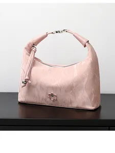 Detailed close-up of pink ruched shoulder bag with flower decoration and silver metal buckle