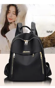 Detail of black oxford backpack showing gold zippers and multiple storage pockets
