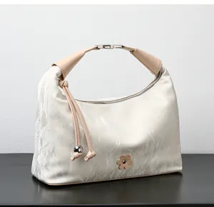 Detail of cream marbled dumpling bag featuring side tassels and silver bead accents