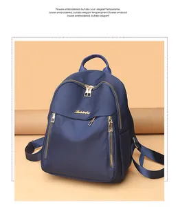 Detail of dark blue nylon backpack featuring gold metal zippers and a spacious main pocket