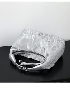 Detail of silver pleated metallic handbag featuring a unique flower metal buckle decoration