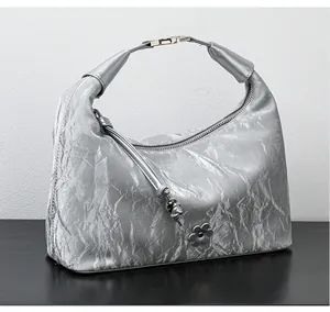 Detail of silver metallic hobo bag featuring crinkled texture and floral tassel charm