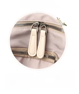 Detailed macro view of the smooth dual silver zippers on the nylon travel backpack