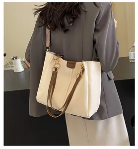 Detail of cream white tote bag with brown straps and golden rings worn by model