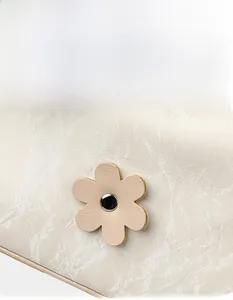 Close-up of floral leather charm with gold rivet on cream marble textured handbag