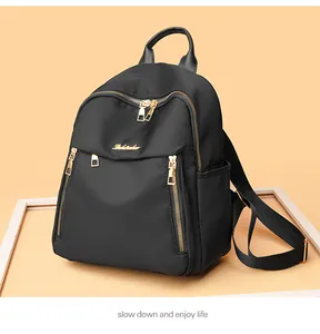 Detail view of black oxford fabric backpack with golden zippers and polished hardware