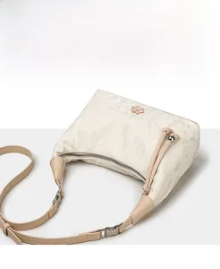 Detail of cream hobo bag with pleated texture and silver flower charm decoration