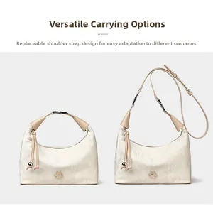 Detail of detachable strap on cream moon bag with floral hardware and marbled texture