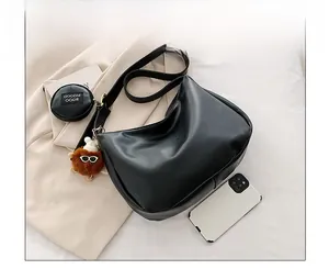 Detail view of black hobo bag with mini round pouch and plush monster charm keychain