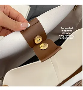 Detail view of the secure magnetic closure on a stylish beige and brown handbag