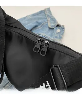 Close-up of smooth black metal double zippers and lettered strap on a nylon bag