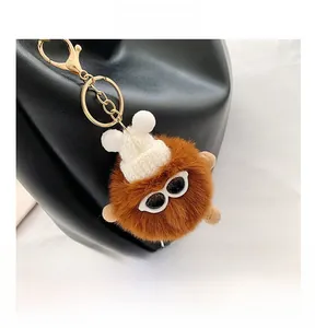 Detail of cute brown plush pompom charm with mini white knit hat and glasses for handbags