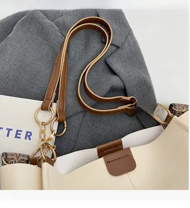 Detail of cream and brown faux leather tote with gold rings and decorative chain