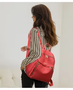 Side view of a vibrant red Oxford fabric backpack with gold zippers worn by a model