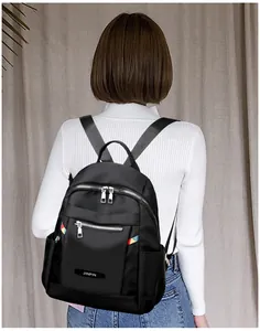 Detail of black oxford backpack featuring silver zippers and stylish striped webbing straps