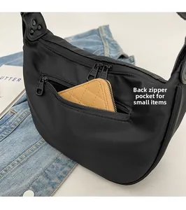 Detail view of the functional back zipper pocket on a black nylon crescent shoulder bag