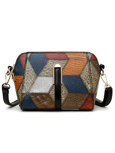 Nahaufnahme der geometrischen Leder-Patchwork-Struktur und des Goldverschlusses der Tasche