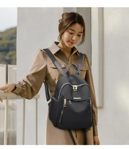 Outdoor lifestyle shot of a black Oxford cloth backpack with gold metal zippers