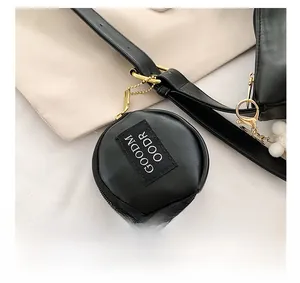 Detail of a small black round leather pouch with GOODMOODR patch and gold chain hardware