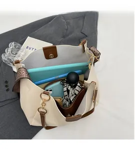 Detail of spacious interior storage in beige tote bag showing tablet and umbrella