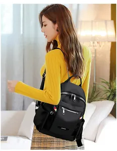 Detail of waterproof black nylon backpack with colorful zipper pullers and metal logo