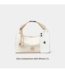 Size comparison between the cream hobo bag and an iPhone 12 to show dimensions