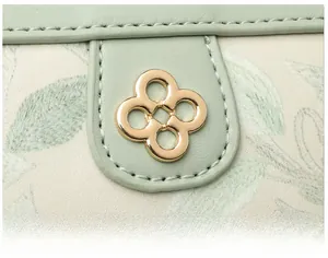 Dettaglio dell'hardware floreale dorato su borsa a tracolla in pelle verde chiaro