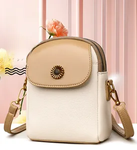 Détail du sac de téléphone beige à grain litchi avec boucle fleurie et bandoulière