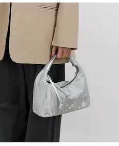 Detail of silver metallic hobo bag featuring crinkled leather texture and floral metal buckle