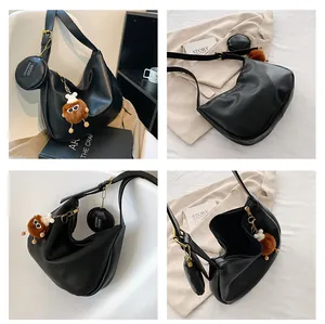Detail of black soft PU leather shoulder bag with plush charm and round coin purse