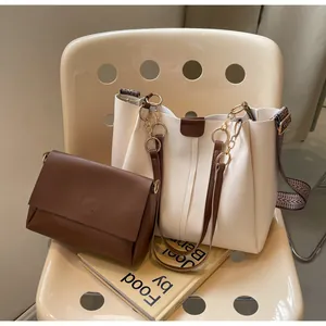 Detail of off-white tote and brown crossbody bag set on a minimalist chair