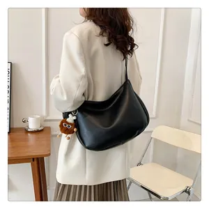 Detail of a black leather hobo bag with a cute brown plush charm on a model