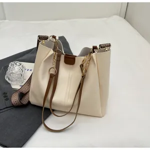 Detail of cream tote bag featuring leather, gold chain, and jacquard woven straps