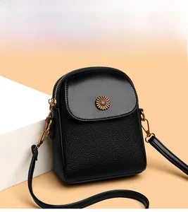 Détail de la pochette téléphone en cuir noir avec boucle dorée en forme de tournesol