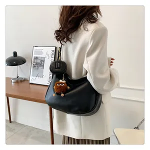 Detail of black crescent moon shoulder bag with plush charm and mini pouch accessory