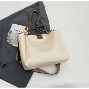 Detail of off-white tote bag with brown handles and geometric wide shoulder strap