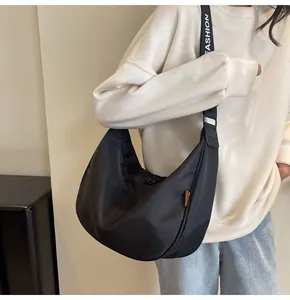 Detail of black crescent crossbody bag featuring wide fashion letter nylon shoulder strap