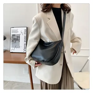 Minimalist black crescent bag shown worn as an underarm shoulder bag for commuting