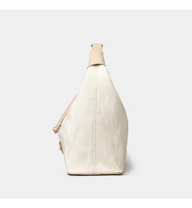 Side view of cream pleated dumpling bag showing minimalist trapezoid shape and soft texture