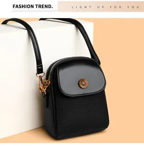 Détail d'un sac à bandoulière noir avec texture litchi et logo tournesol doré