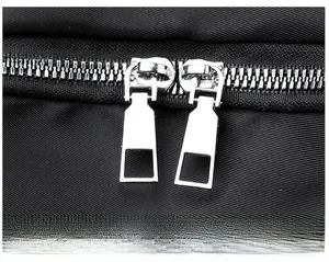 Detailed close-up of smooth silver-tone double zippers on a black oxford fabric backpack
