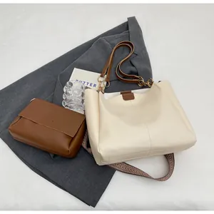 Detailed shot of cream tote bag and brown flap bag set on stylish grey blazer background