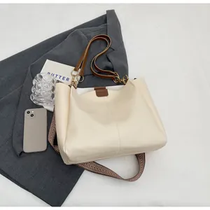 Detail of cream tote bag with contrast stitching and patterned woven shoulder strap