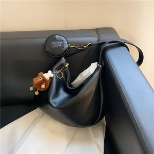 Minimalist black crescent canvas hobo bag with a plush bear charm and coin purse