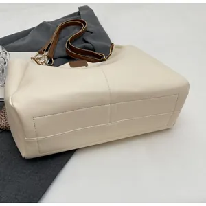 Detail view of cream tote bag base with brown straps and golden metal rings