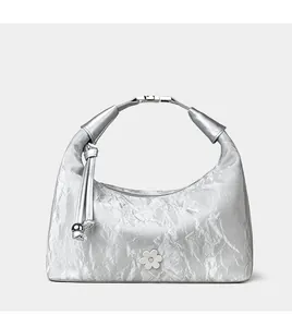 Close-up of silver dumpling bag showing metallic pleated texture and floral emblem